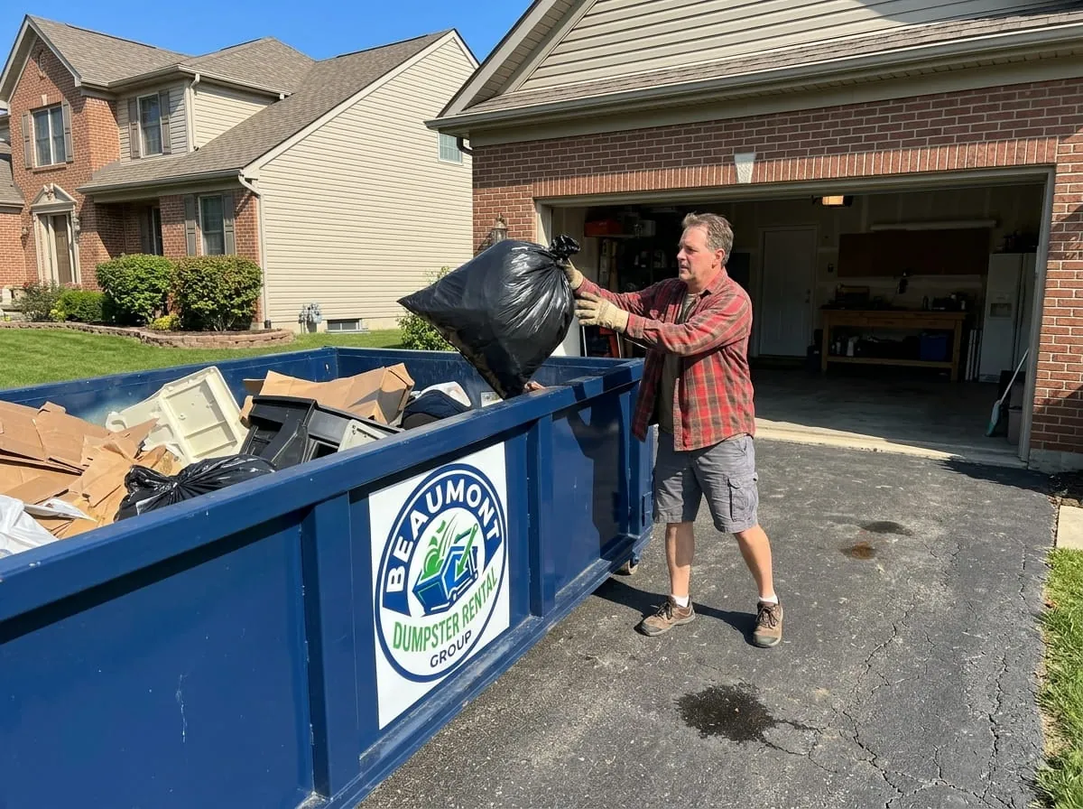 Homeowner loading a bag of household junk into a roll-off dumpster in Beaumont, Texas Homeowner loading a bag of household junk into a roll-off dumpster in Beaumont, Texas